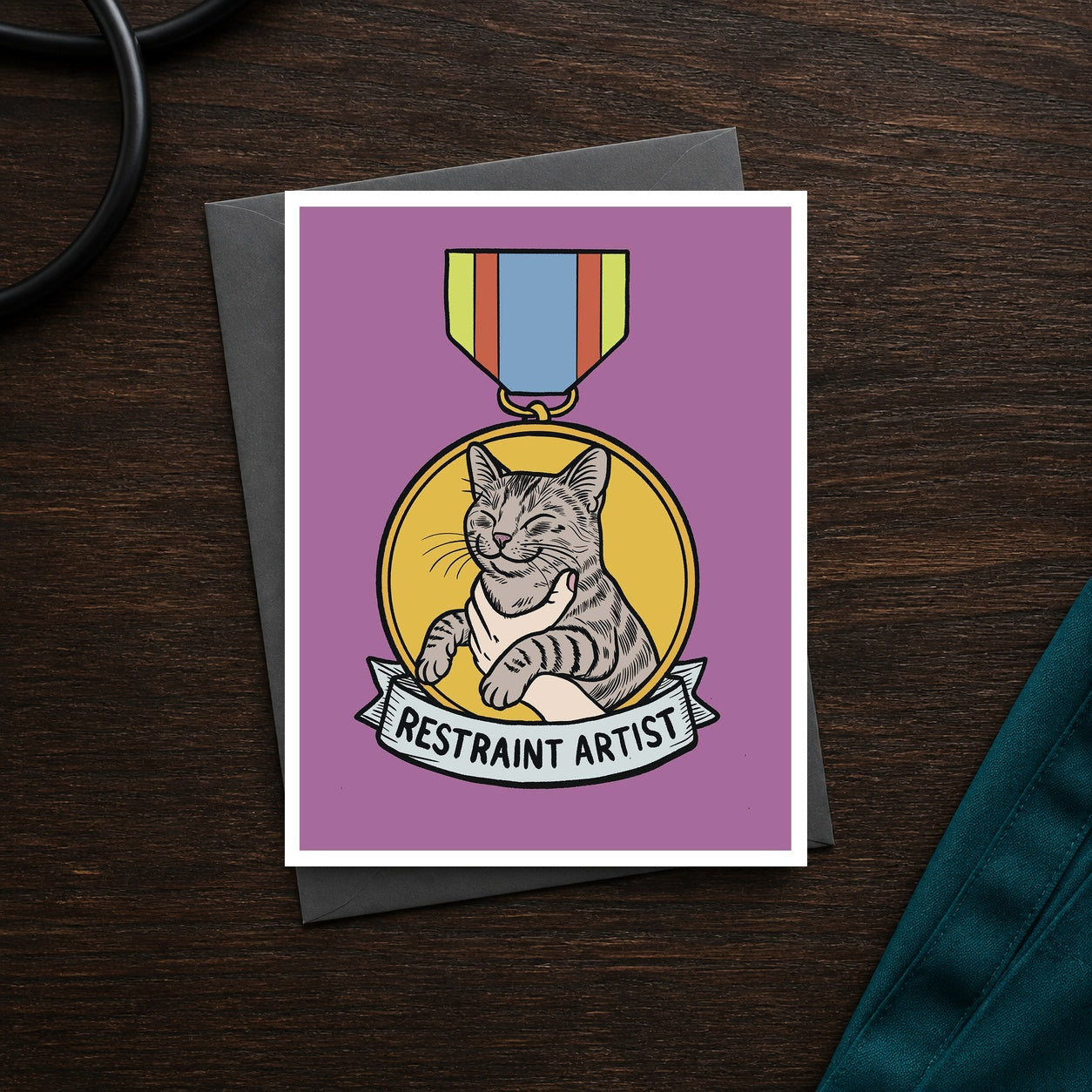 Restraint Artist A2 veterinary recognition notecard front on a dark clinic desk