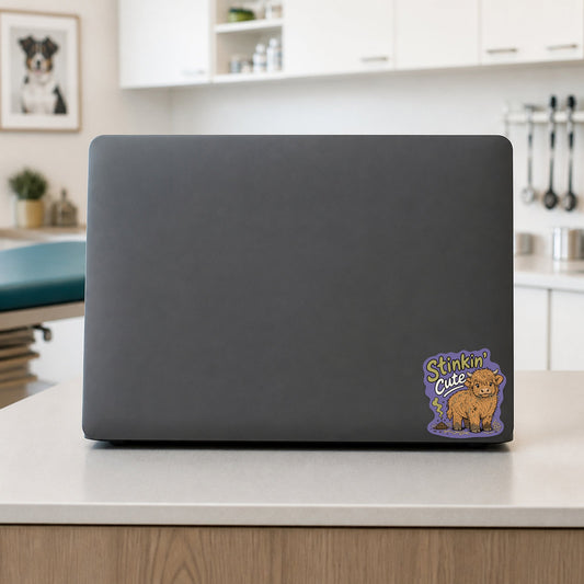 🐮 Stinkin' Cute Highland Cow – Funny Vet Sticker shown on a veterinary clinic laptop