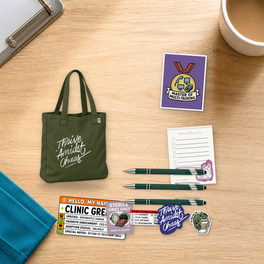 Thrive Amidst Chaos deluxe veterinary shift bundle with an olive tote, card, notepad, pens, and stickers, arranged on a light oak desktop for veterinary professionals