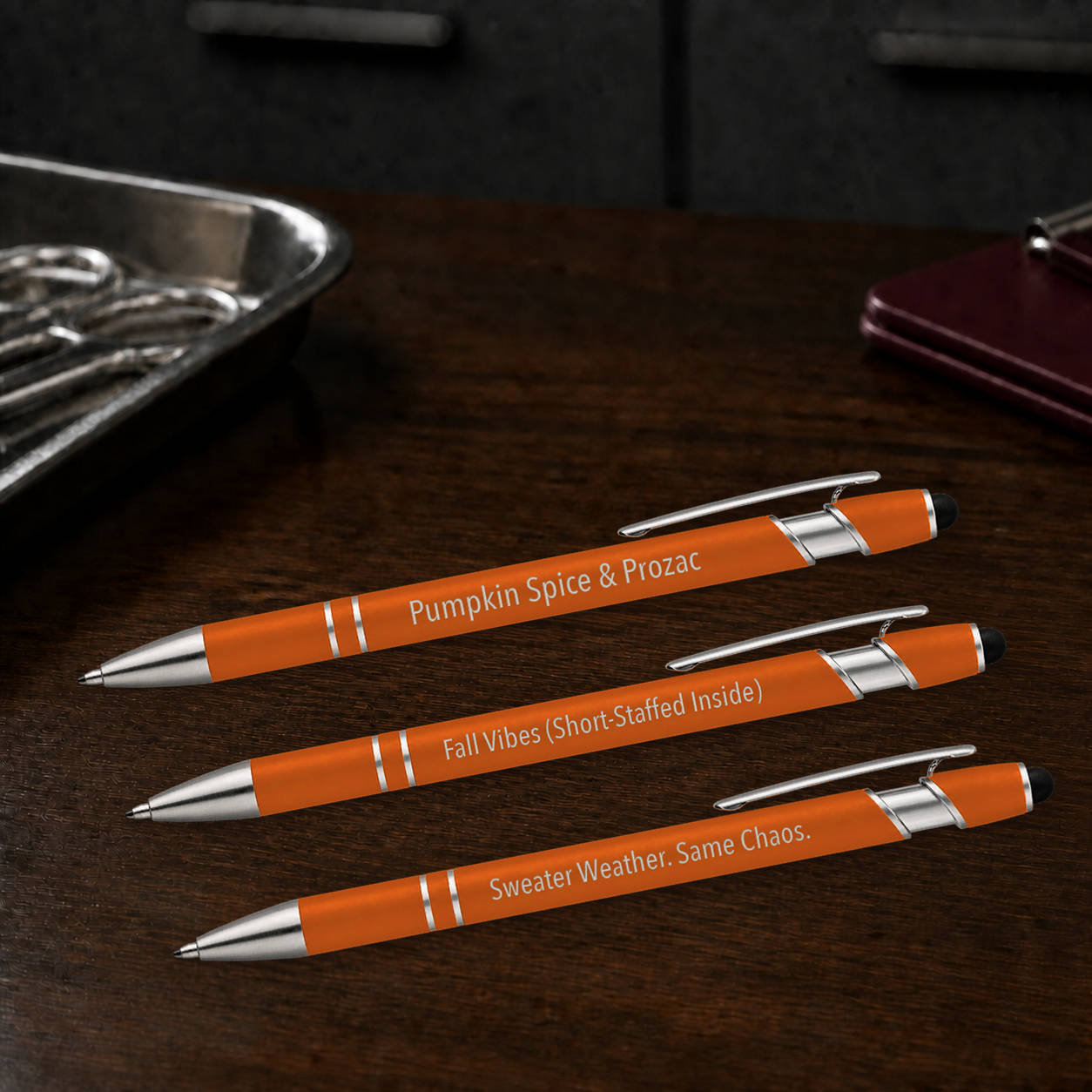 Fall Pen 3-Pack orange veterinary gel pens engraved Pumpkin Spice and Prozac, Fall Vibes and Sweater Weather on a dark clinic table