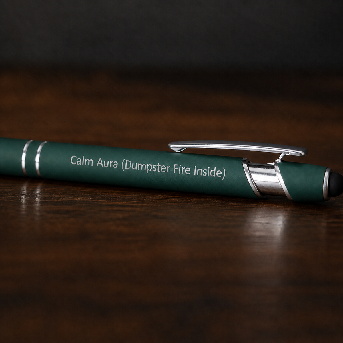 Close view of a dark green Calm Aura Dumpster Fire Inside pen with silver laser engraving