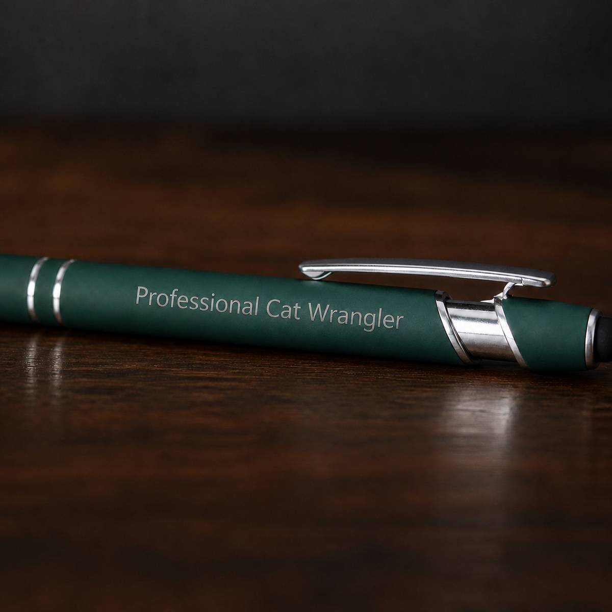 Close view of a dark green Professional Cat Wrangler pen with silver laser engraving