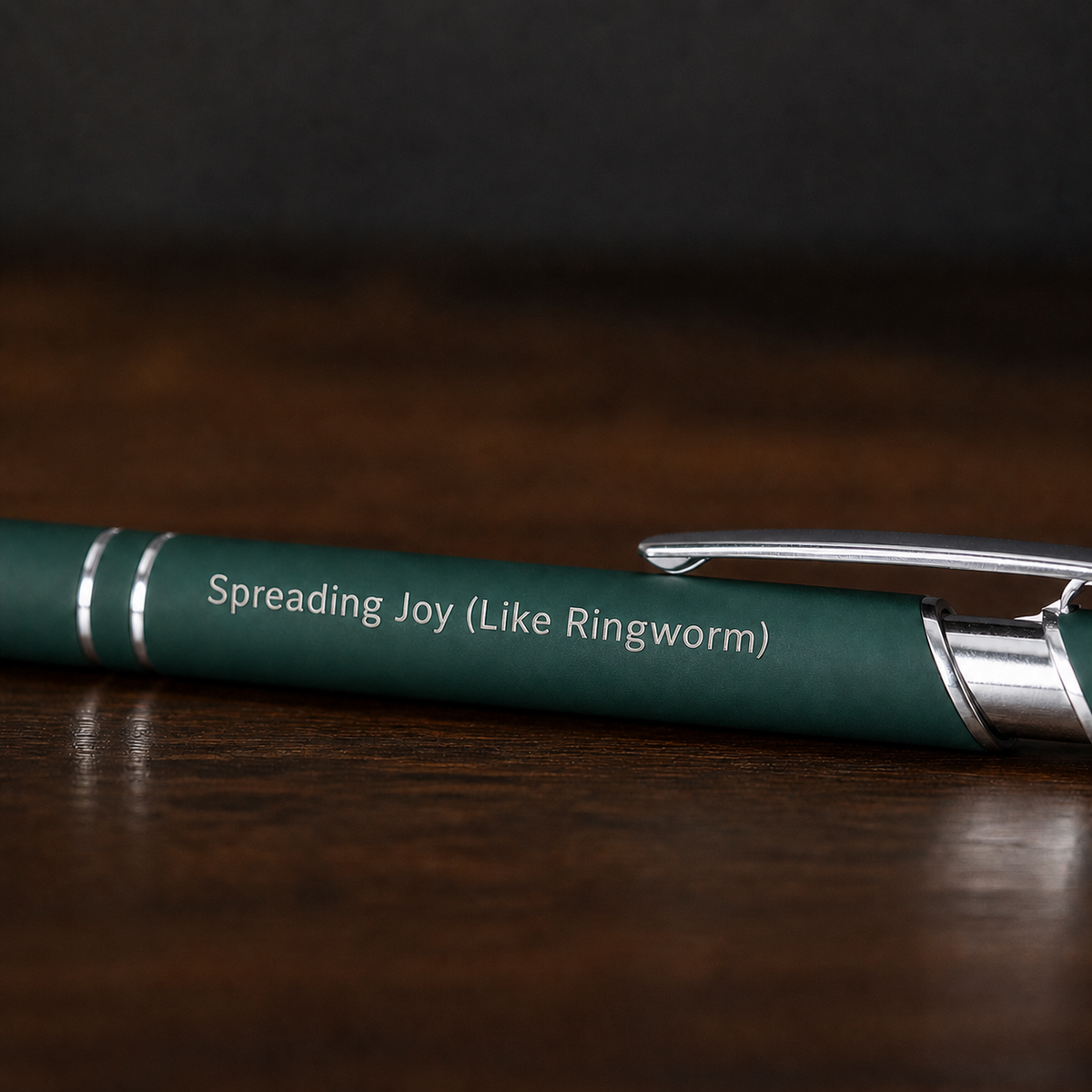 Close view of a dark green Spreading Joy Like Ringworm pen with silver laser engraving