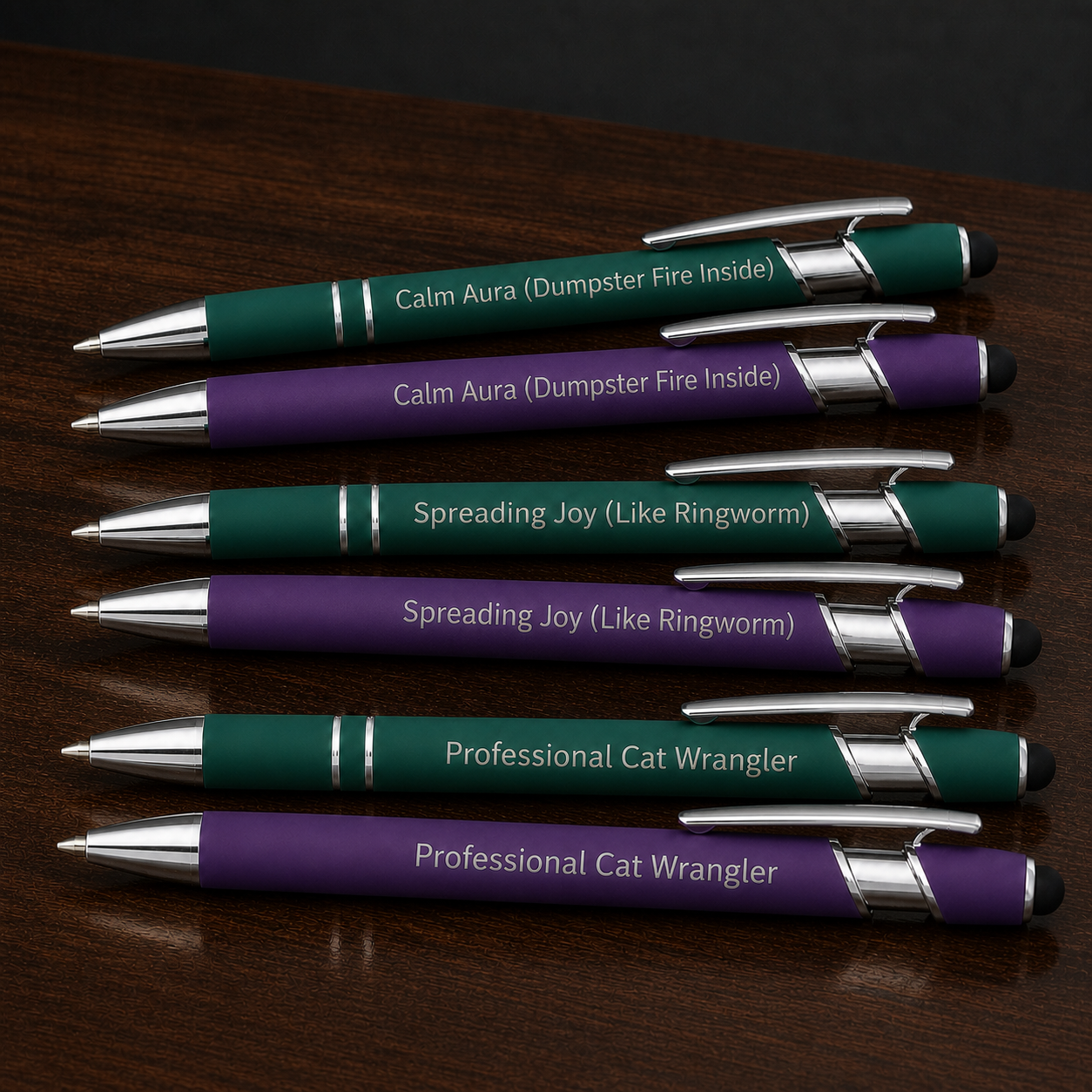 Close view of six green and purple veterinary pens with silver laser engraving and stainless steel hardware